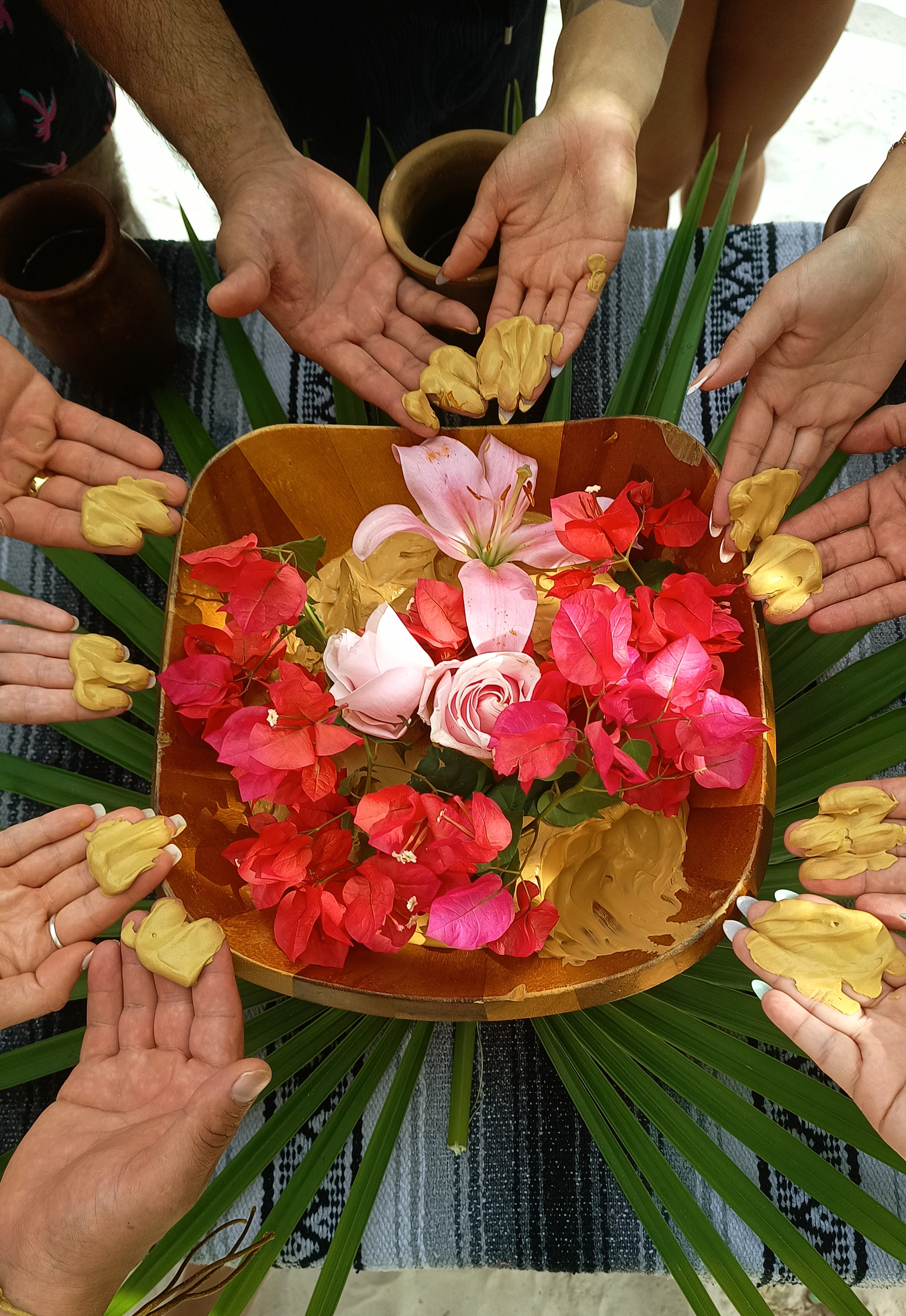 Circle of hands around flowers in ceremony