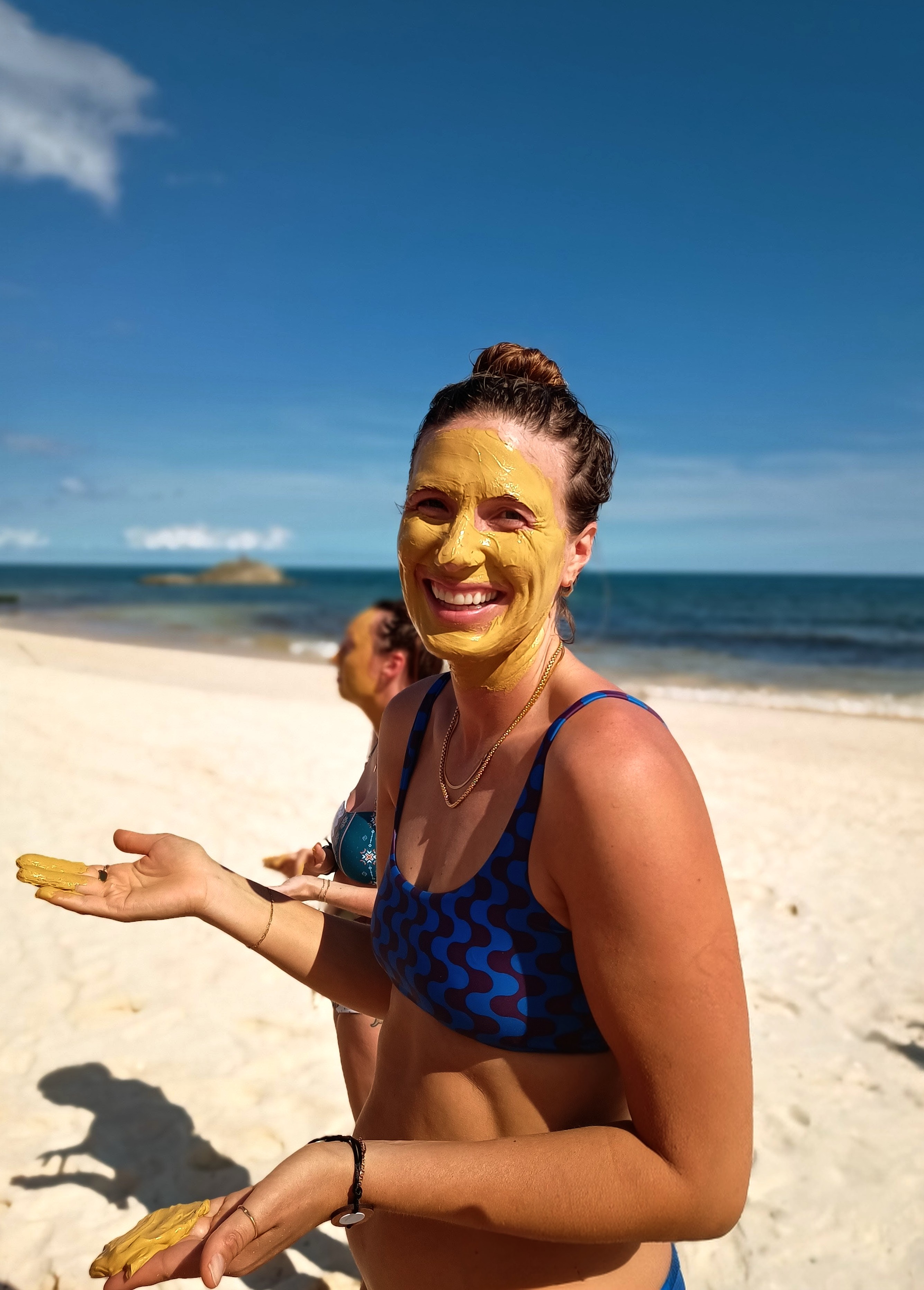 Woman with gold face mask smiling on the beach
